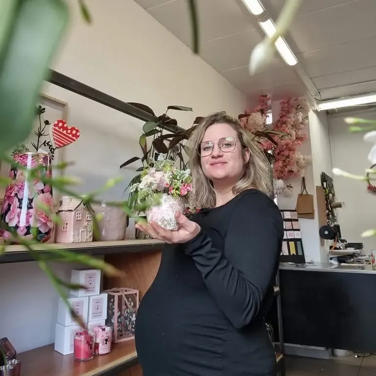 Mimie Brindille dans sa boutique tenant une composition florale